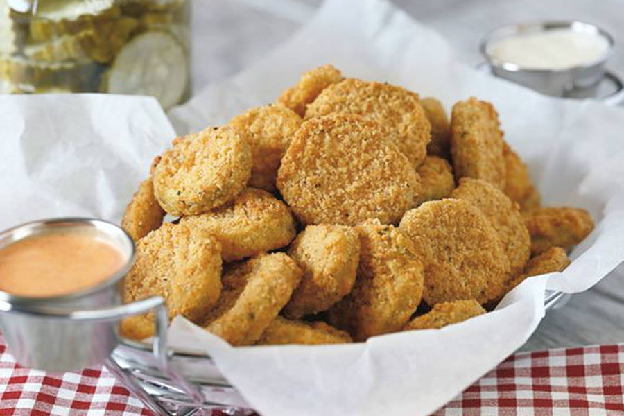 Basket of lightly golden breaded mild pickle chips with dipping sauce